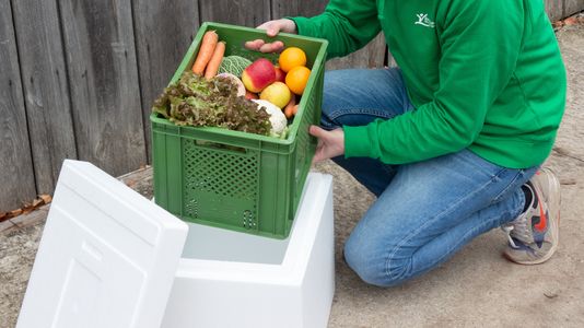 Person stellt Gemüsekiste in Isobox