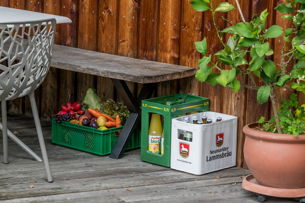 KI generiert: Kisten mit Gemüse, Saft und Bierkästen unter einer Bank auf einer Terrasse. Text: "Neumarkter Lammsbräu".