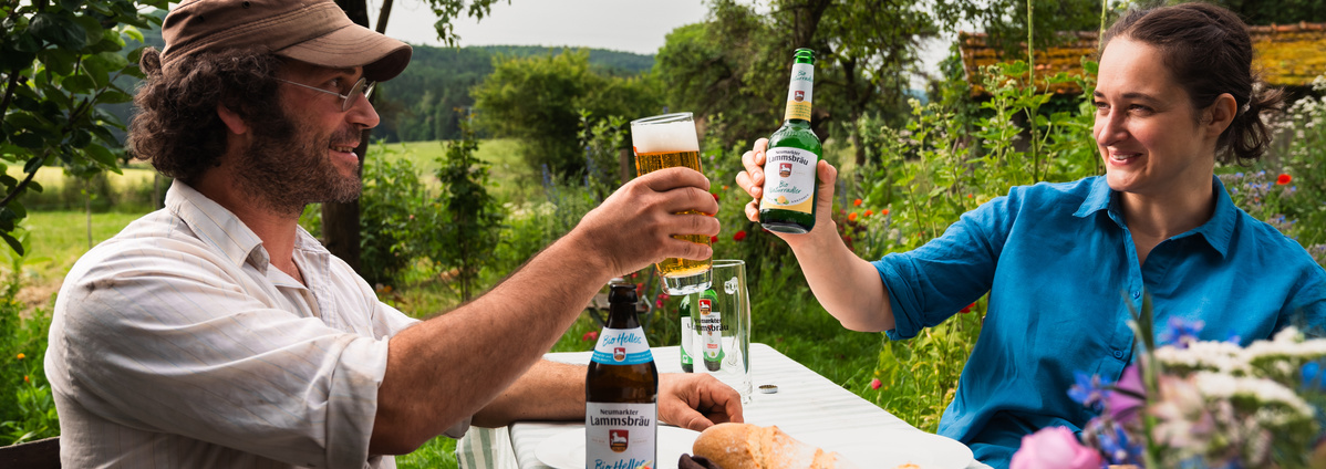 Zwei Personen stoßen mit Bier von Neumarkter Lammsbräu an. Foto: Neumarkter Lammsbräu