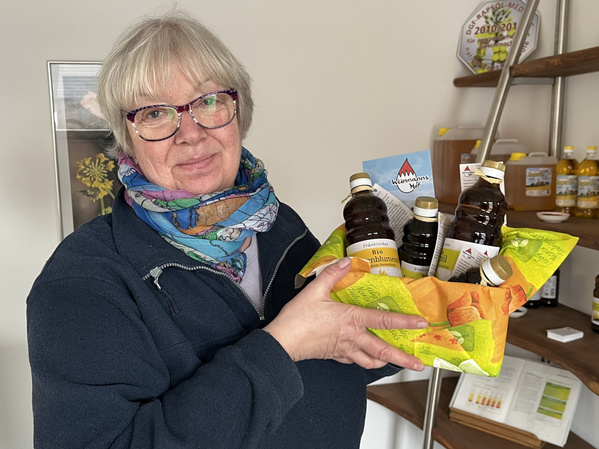 Martina Weinmann hält Geschenkkorb mit den Ölen vom Weinmannshof hoch