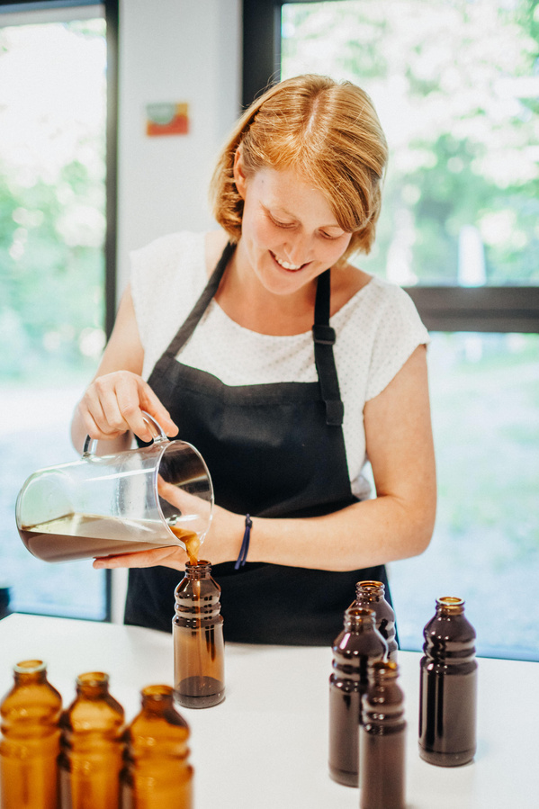 Jule füllt Bio-Öl in Glasflaschen ab
