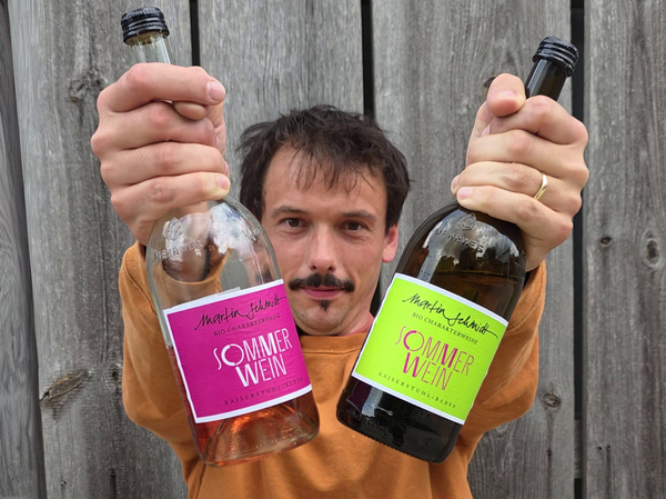 Person hält zwei Weinflaschen in die Kamera