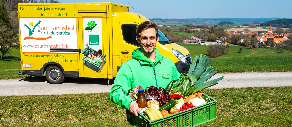 David Baumann mit Ökokiste vor Lieferauto