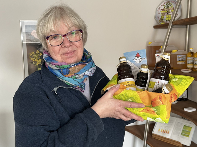 Martina Weinmann hält Geschenkkorb mit den Ölen vom Weinmannshof hoch