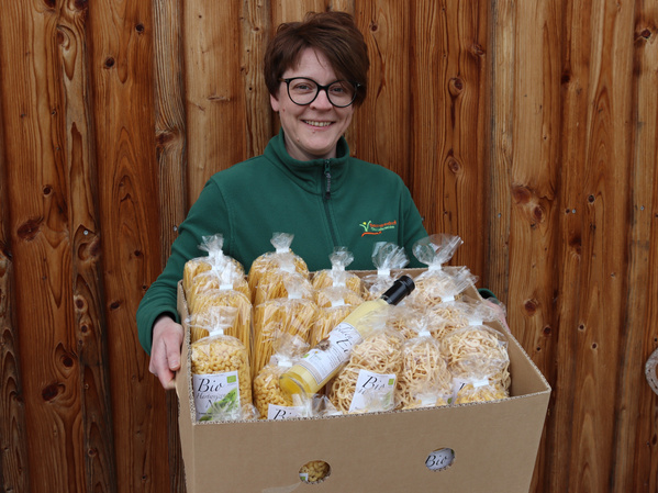 Mitarbeiterin des Baumannshofs hält Bananenkarton mit Nudeln in den Händen
