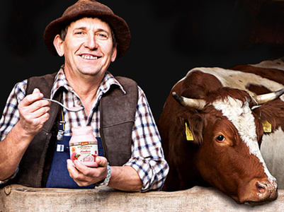 Mann mit Joghurtglas von den Schrozberger Milchbauern neben Kuh