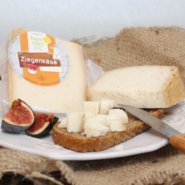 KI generiert: Ein Teller mit Ziegenkäse, Feigen und Brot auf einem rustikalen Tuch. Text: "Ziegenkäse".