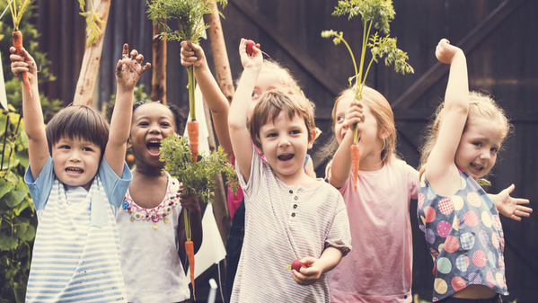 Kinder mit Karotten freuen sich - frisches Gemüse