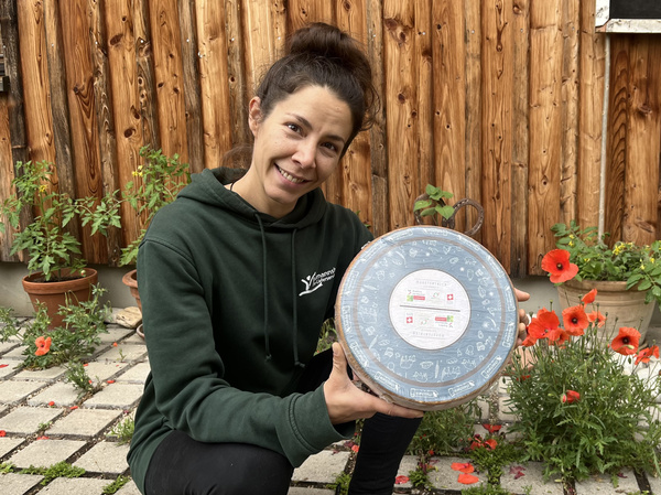 Mitarbeiterin hält Käselaib Muma Veglia in den Händen