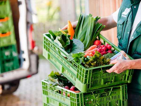 Person nimmt Ökokiste von einem Stapel Kisten