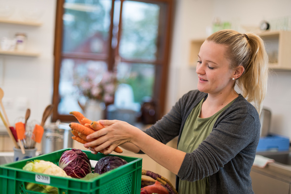 Frau räumt in Küche Ökokiste aus