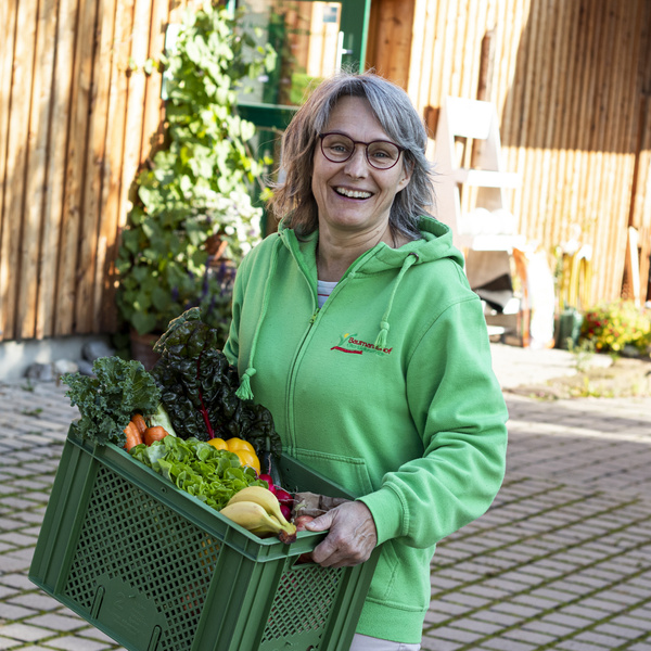 Jutta Baumann trägt Obst und Gemüsekiste