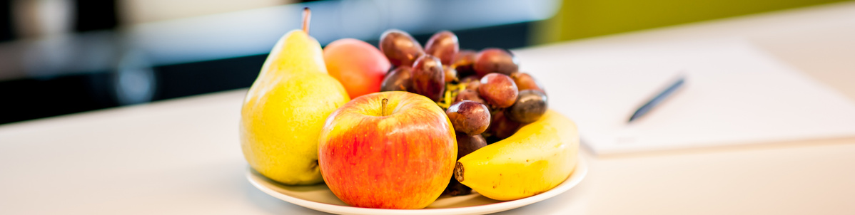 Teller mit Obst steht auf einem Schreibtisch