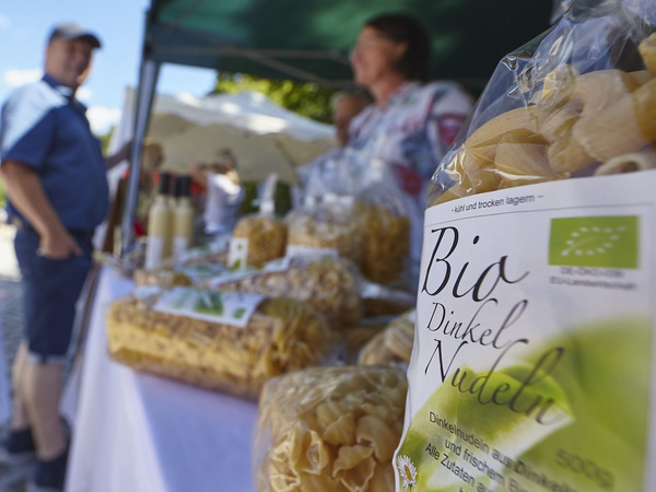 KI generiert: Verkaufsstand mit Bio-Dinkel-Nudeln; Text: „Bio Dinkel Nudeln“.