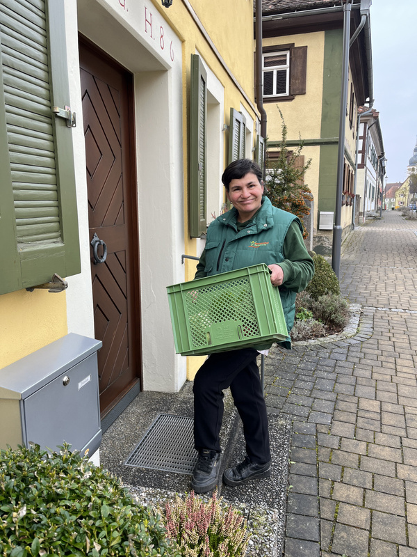 Marie mit Ökokiste vor Haustür