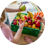 Kinder greifen nach Obst aus einer Ökokiste